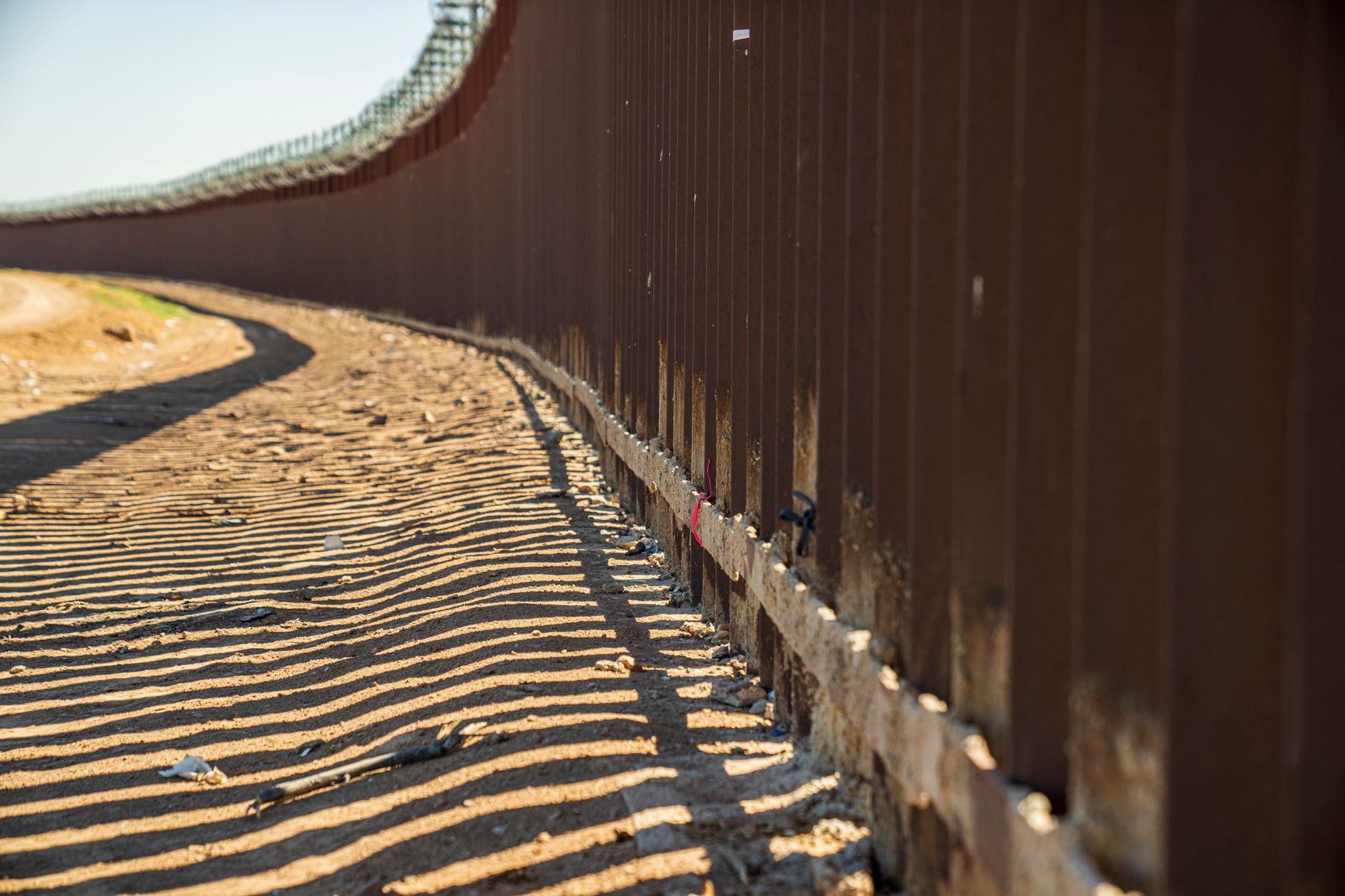 A line of EU border officers conducting biometric screening of migrants at an external frontier checkpoint.